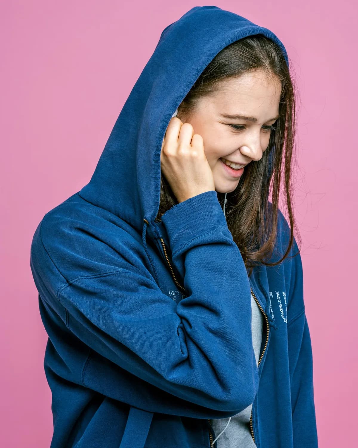 Modelo de moletom azul com capuz sobre fundo rosa